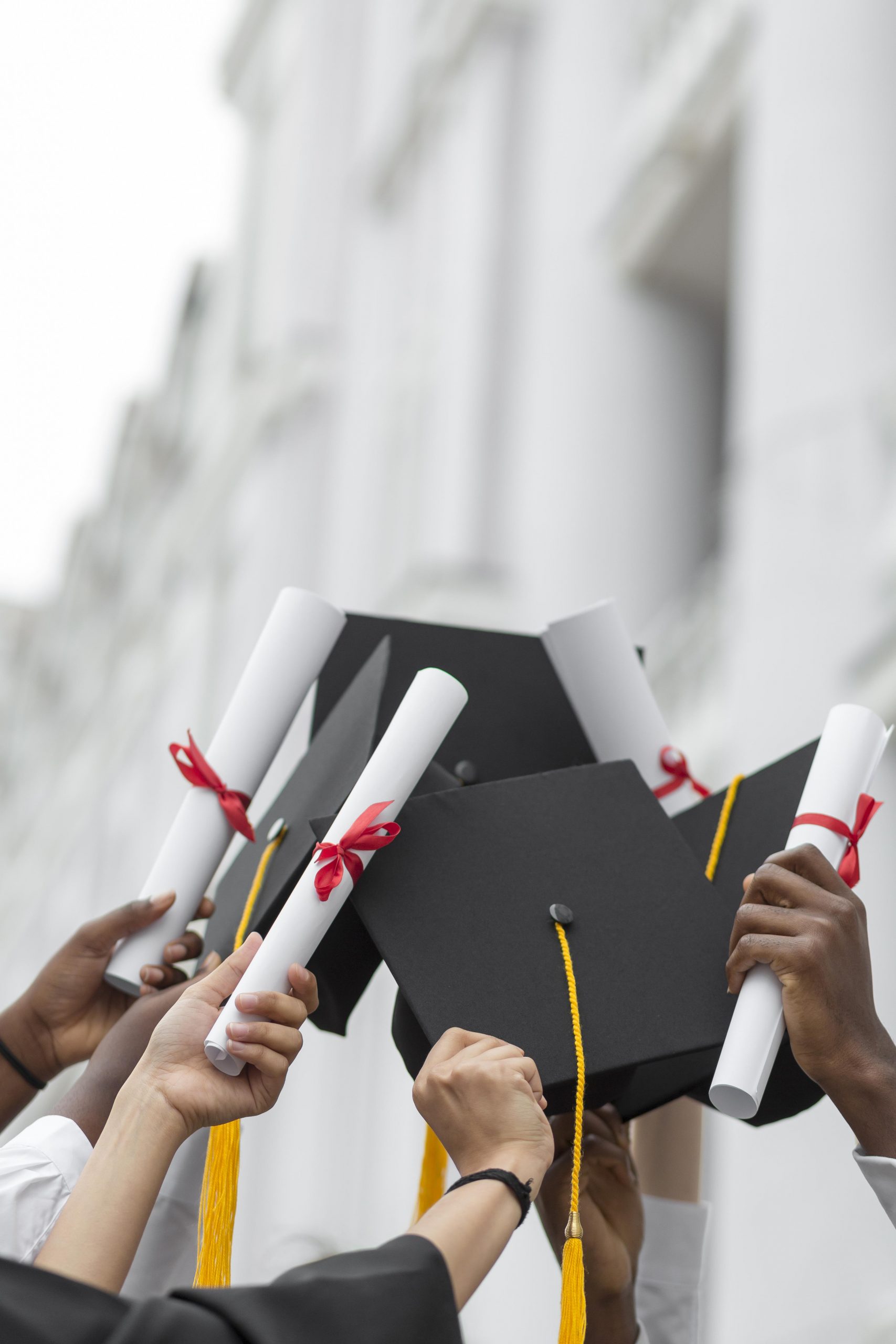 close up hands holding diplomas caps scaled